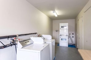 Ein Waschraum mit zwei Waschmaschinen, einem Trockner und einem Hauswirtschaftsraum mit Warmwasserbereiter.