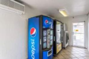 A hallway with vending machines, including a Pepsi machine, and a door leading to another room. - Cozy 2-Bed Smoking Room (Albuquerque)