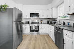A modern kitchen with white cabinetry, stainless steel appliances, and a wooden floor. - Cincy 5BR Escape Zoo Xavier Sleeps 7 (Cincinnati)