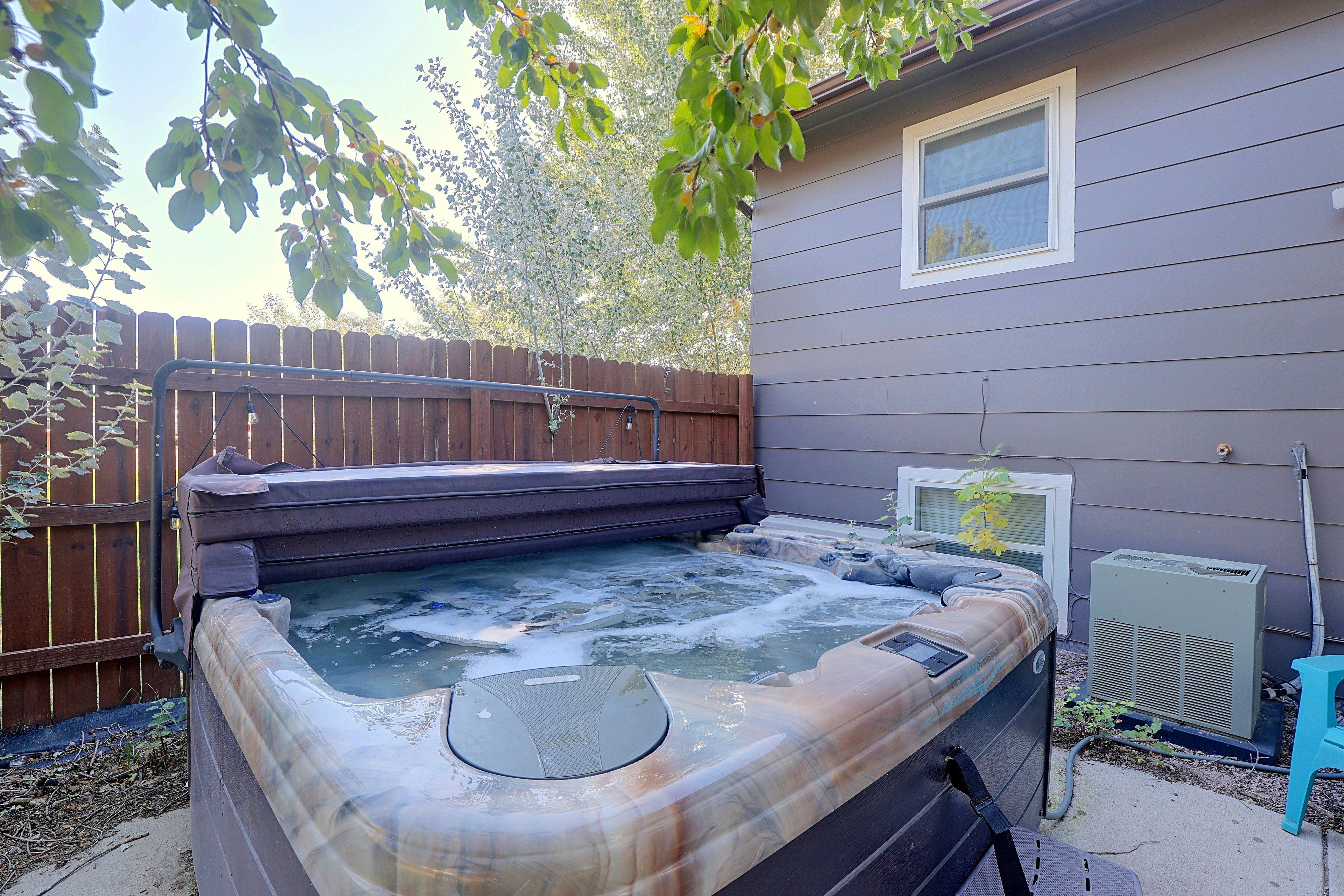 Ein Whirlpool in einem Garten mit Holzzaun und einem Haus im Hintergrund.