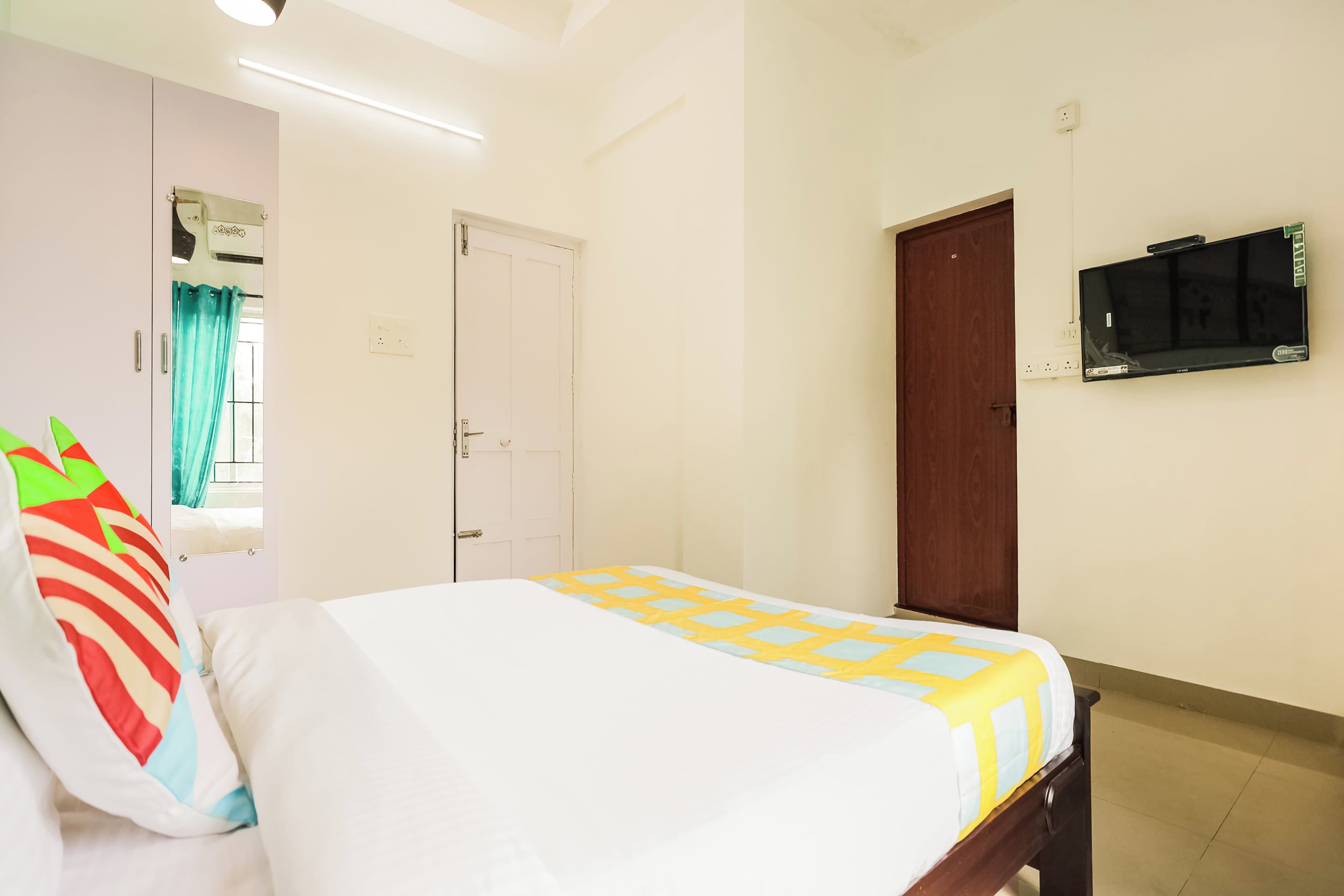Un dormitorio con cama, armario, televisor y puerta.