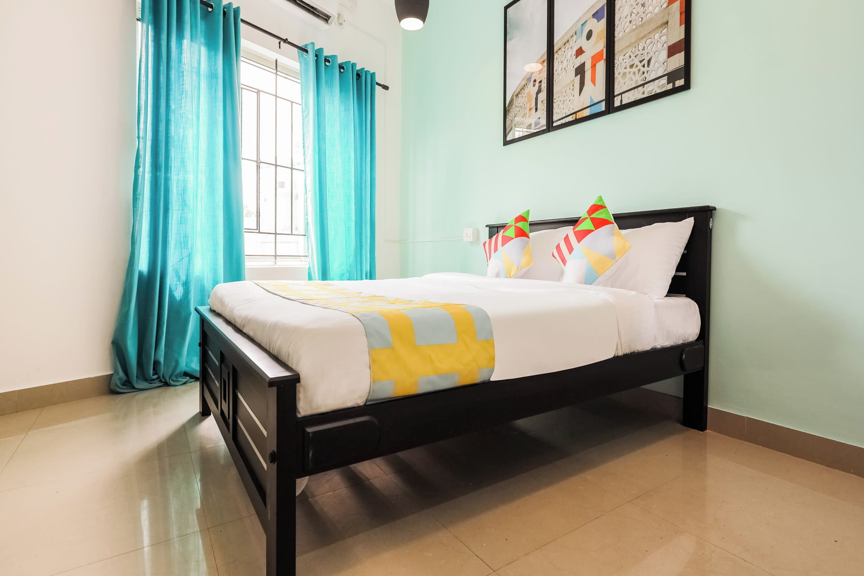 A bedroom with a bed, curtains, a window, and wall art.
