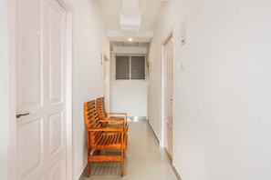 Um corredor com portas brancas, um banco e uma janela com persianas.