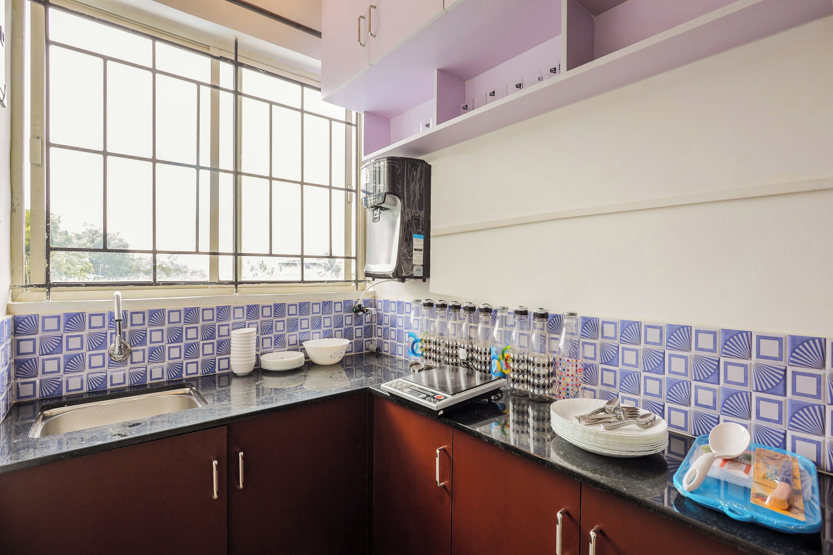 Una cocina con ventana, dispensador de agua y lavamanos.