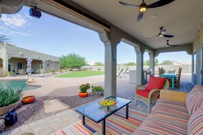 A covered outdoor patio with a pool, seating area, and a view of the surrounding landscape. - Desert Hills Fenced Acre! Pool, Spa + Dogs Allowed (New River)