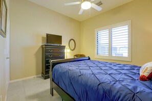 A bedroom with a bed, dresser, TV, and a window with blinds. - Desert Hills Fenced Acre! Pool, Spa + Dogs Allowed (New River)