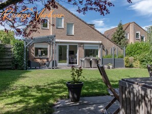 A residential property with a covered patio, a lawn, and a potted plant. - Holiday Apartment With 2 Bedrooms (Nieuwvliet)