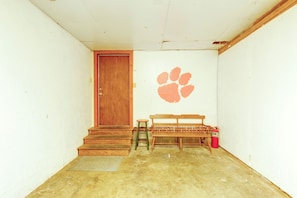 A room with a wooden door, a bench, a fire extinguisher, and a wall with a paw print. - Walk to the Stadium & Clemson: 3BR w/ Parking! (Clemson)