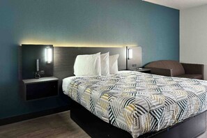 A modern hotel room with a large bed, a bedside table, a nightstand, and a wall-mounted lamp. - 1 Full Bed | Non-Smoking (LEBEC)