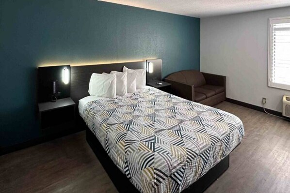 A modern bedroom with a bed, bedside tables, a chair, and a window.