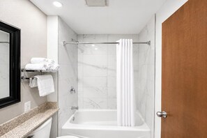 A bathroom with a bathtub, a shower, and a toilet. There are towels on a rack and a mirror on the wall.