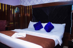 Une chambre d’hôtel avec un lit, une tête de lit en bois et un mur décoré d’un motif.