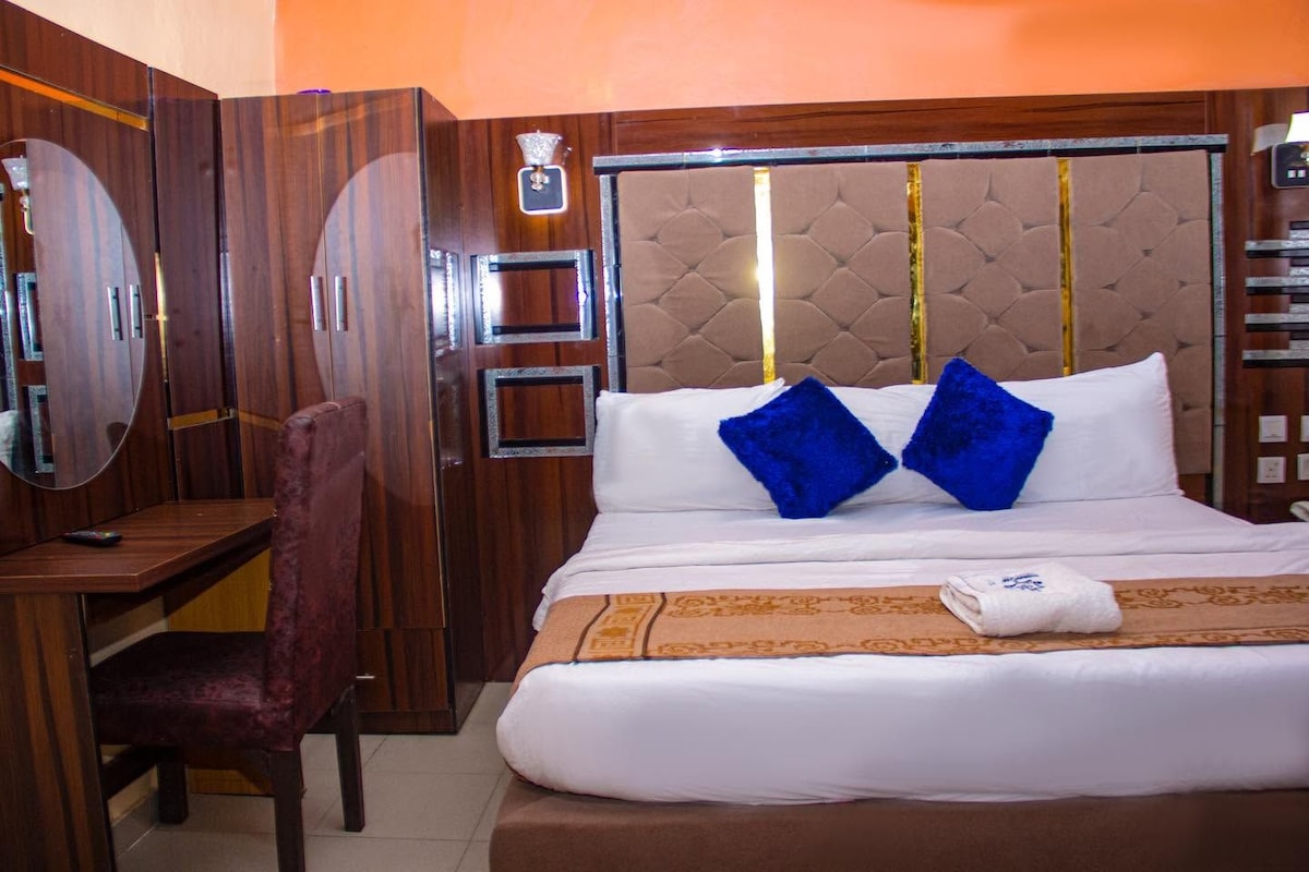 Une chambre d’hôtel comprenant un lit, un bureau, une chaise, un miroir et une armoire.