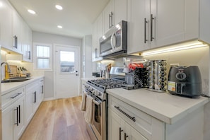 A modern kitchen with white cabinetry, a stainless steel stove, and a microwave. - Lynwood Retreat Near LA, SoFi Stadium & Beaches (Lynwood)