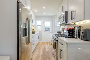 A modern kitchen with stainless steel appliances, white cabinetry, and a wooden floor. - Lynwood Retreat Near LA, SoFi Stadium & Beaches (Lynwood)