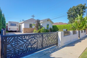 A residential area with a white house, a parked RV, and a decorative metal fence. - Lynwood Retreat Near LA, SoFi Stadium & Beaches (Lynwood)