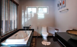 Un bagno moderno con vasca, servizi igienici e una finestra.