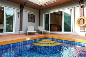 Une piscine avec une terrasse en bois, une chaise longue et un cercle de sauvetage.