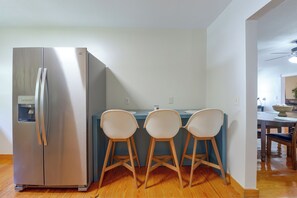 A kitchen with a stainless steel refrigerator, a blue countertop, and three white chairs. - Beach Escape 1 Mi to Okaloosa Island & Dtwn (Fort Walton Beach)