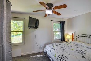 A bedroom with a bed, a ceiling fan, a TV mounted on the wall, and two windows with curtains. - Lakefront Escape in Vandalia: Ski, Fish & Stargaze (Vandalia)
