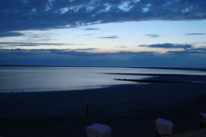 Een strand met een rustige zee, een heldere lucht en enkele stoelen langs de kust.
