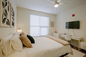A bedroom with a bed, a desk, a chair, a television, and a ceiling fan. - Walk to Gaslamp & Petco Park! Dtwn Apt w/ Balcony (San Diego)