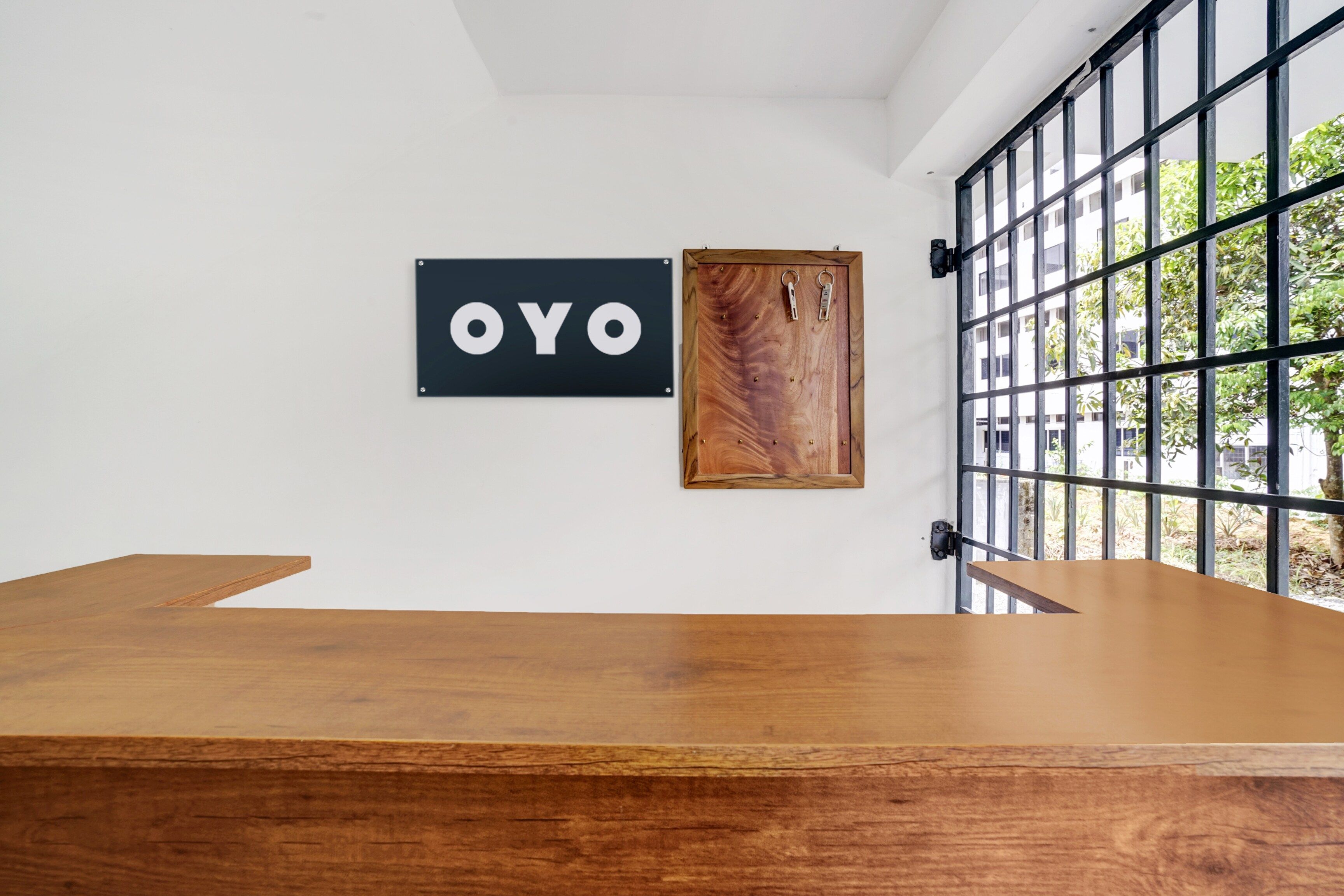 A room with a wooden table, a black sign with 'OYO' on it, and a wooden door with metal hinges.