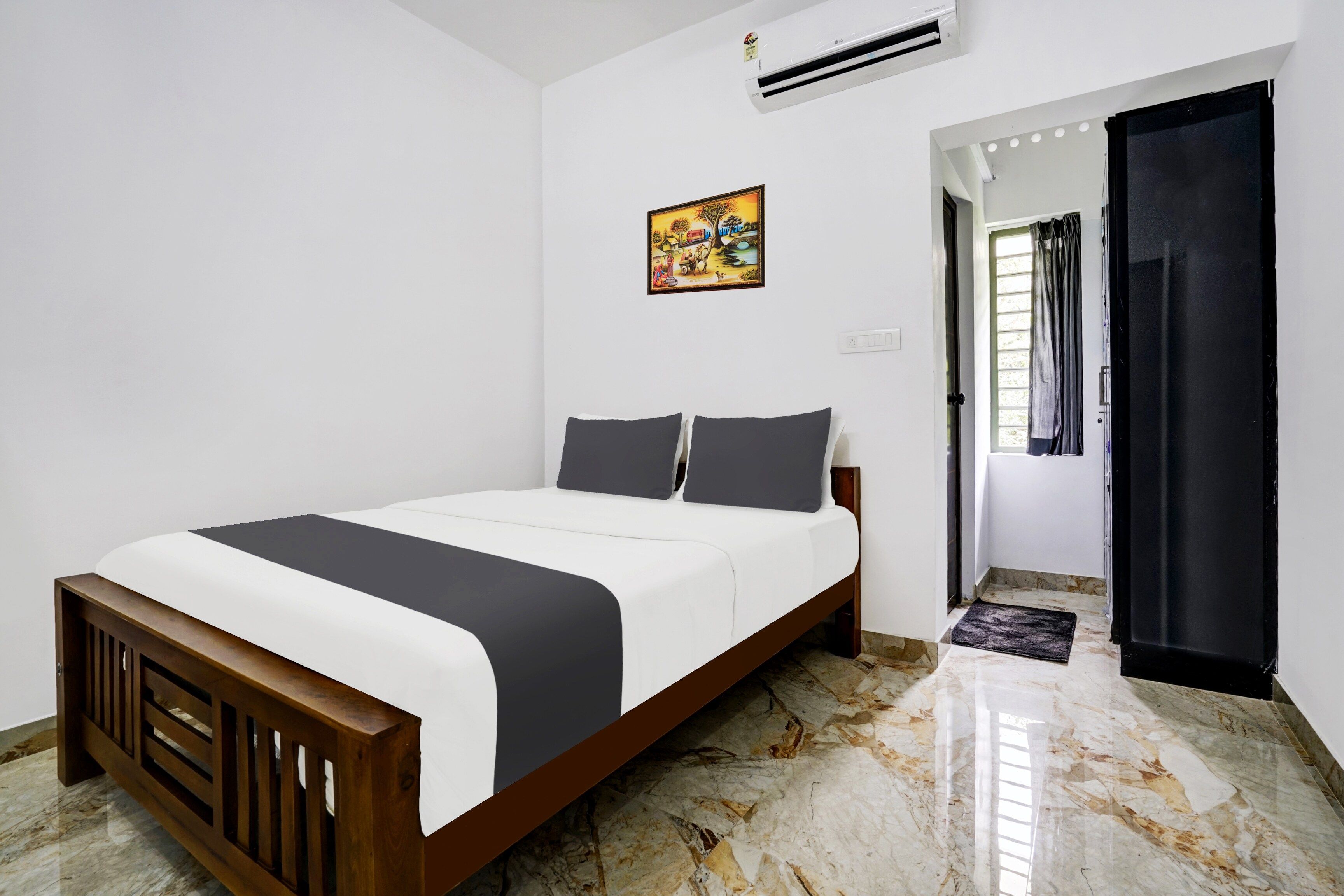 A bedroom with a bed, a painting, an air conditioner, and a door leading to another room.
