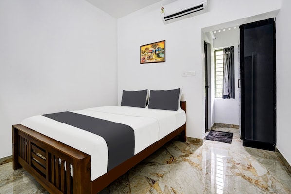 A bedroom with a bed, a painting, an air conditioner, and a door leading to another room. - Hotel O EVA RESIDENCY (Kochi)