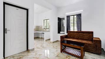 Una sala moderna con un sofá y una mesa de centro, una puerta y vistas a una zona de cocina.