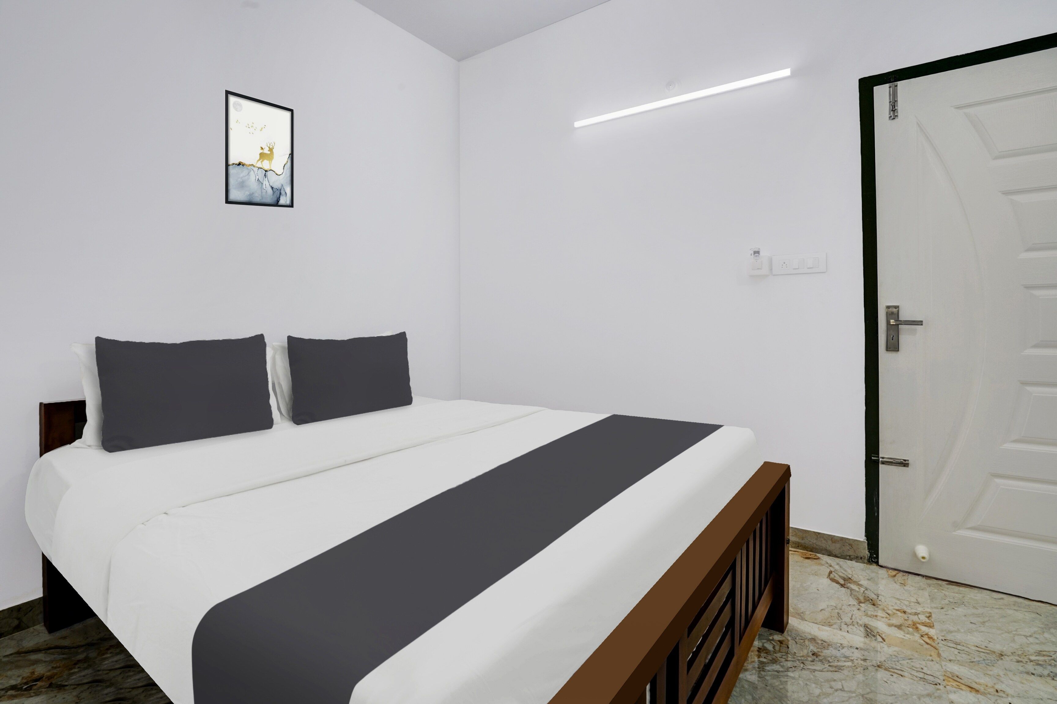 Un dormitorio con cama, una puerta y una lámpara fijada a la pared.