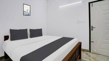 Un dormitorio con cama, una puerta y una lámpara fijada a la pared.