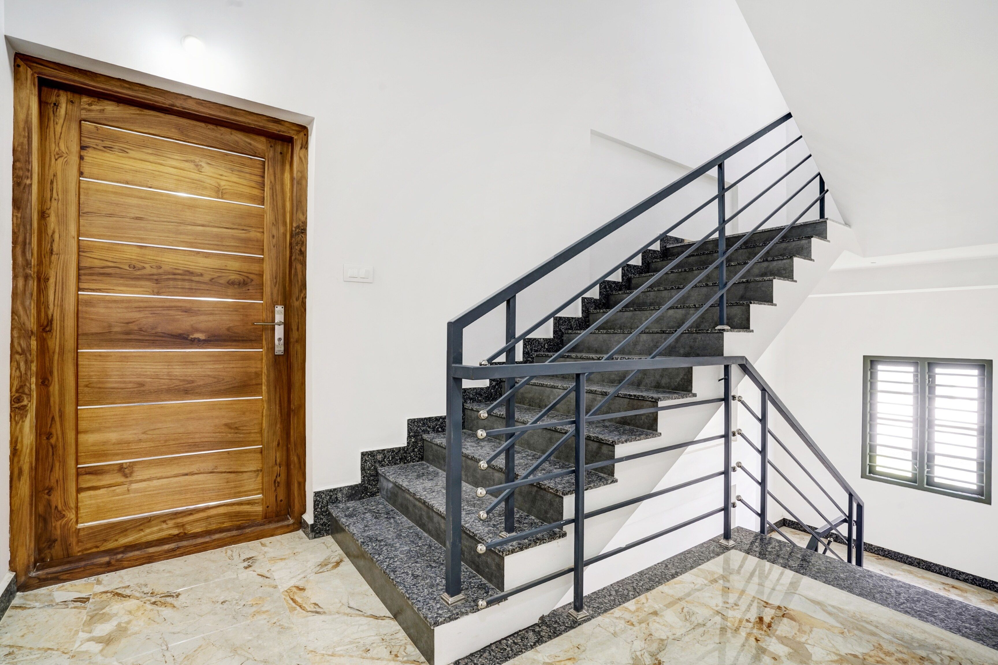 Una escalera con barandilla metálica y una puerta de madera.