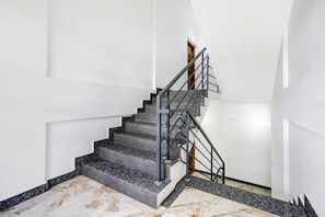 A staircase with a metal railing, marble steps, and a wooden door at the top. - Hotel O EVA RESIDENCY (Kochi)