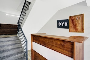 Una escalera con barandilla de madera y un letrero blanco y negro en la pared que dice 'OYO'.