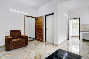 A modern interior with a marble floor, a brown sofa, and a wooden door. - Hotel O EVA RESIDENCY (Kochi)