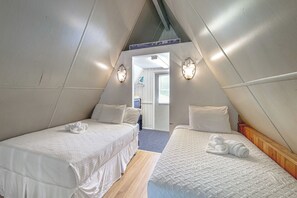 A triangular room with two beds, each with white bedding and towels, and two wall-mounted light fixtures. - 'Livin' on Sunshine' Lake Louisa Escape! (Clermont)