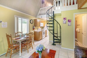 A dining area with a wooden table and chairs, a kitchen with wooden cabinets, and a staircase leading to an upper level. - 'Livin' on Sunshine' Lake Louisa Escape! (Clermont)
