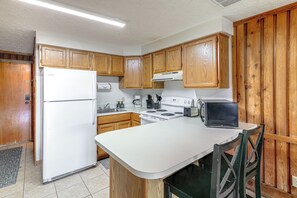 Eine Küche mit Holzausstattung, einem weißen Kühlschrank, einem Herd und einem Toaster.