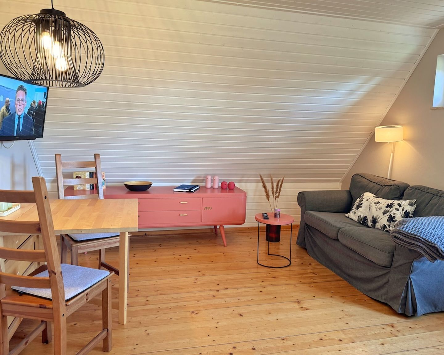 Ein Loft-Wohnraum mit Essbereich, einer Couch und einem an der Wand befestigten Fernseher.