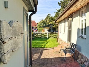 A residential property with a paved patio, a bench, a wooden fence, and a car parked in the background. - defaultName (Glowe)