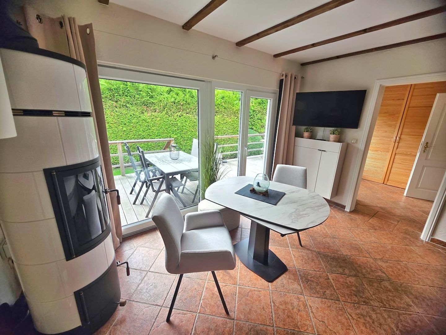 A modern kitchen with a built-in oven, a dining area with a table and chairs, and a large sliding glass door leading to a balcony.