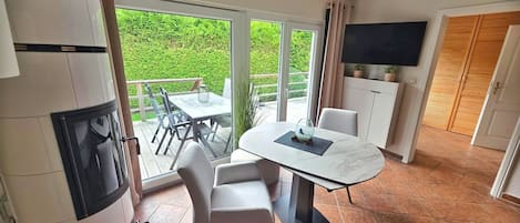 A modern kitchen with a built-in oven, a dining area with a table and chairs, and a large sliding glass door leading to a balcony.
