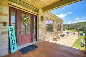 A stone house with a wooden porch, a welcome sign, and a view of the surrounding landscape. - Fredericksburg House & Cabin 10 Mi to Main St (Fredericksburg)