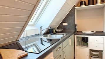 A modern kitchen with a skylight, stainless steel appliances, and a wooden cutting board.