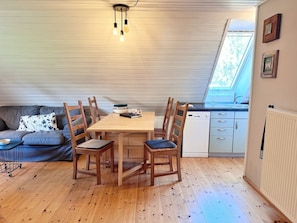 A compact kitchen with a dining area, wooden furniture, and a skylight. - defaultName (Glowe)