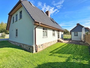 A two-story house with a sloped roof, a stone foundation, and a well-maintained lawn. - defaultName (Glowe)