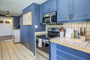 A kitchen with blue cabinets, a microwave, stove, and various kitchen utensils. - McKenzie River Home w/ Waterfront Fire Pit (Vida)
