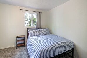A bedroom with a bed, a window, a nightstand, and a view of the outside. - McKenzie River Home w/ Waterfront Fire Pit (Vida)