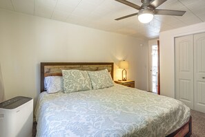 A bedroom with a bed, a ceiling fan, a nightstand with a lamp, and a door. - McKenzie River Home w/ Waterfront Fire Pit (Vida)